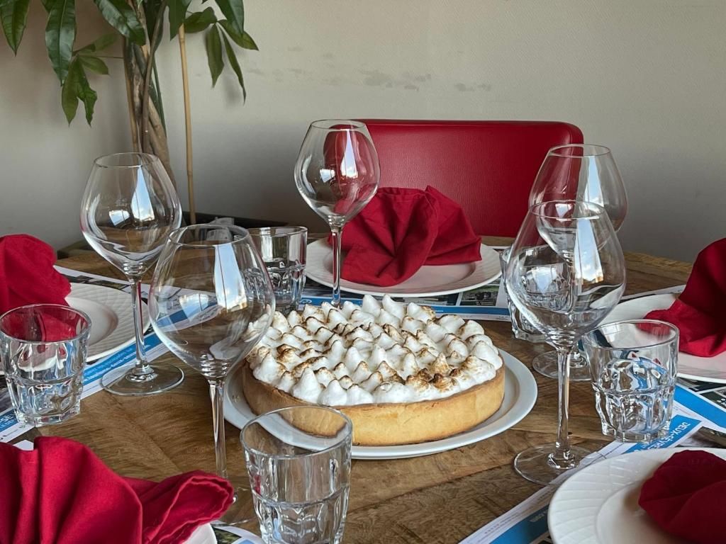 Una mesa de comedor con postre, copas de vino y servilletas rojas.