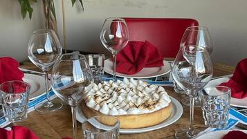 Una mesa de comedor con postre, copas de vino y servilletas rojas.
