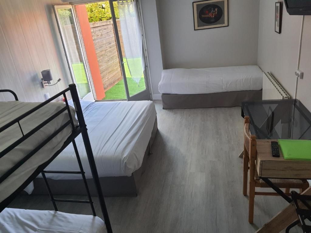 A dormitory room with bunk beds, a small table with a chair, and a sliding glass door leading to an outdoor area.