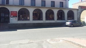 Um edifício com uma fileira de janelas em arco e uma placa para 'Le Cheval Blanc Hotel & Restaurant'.