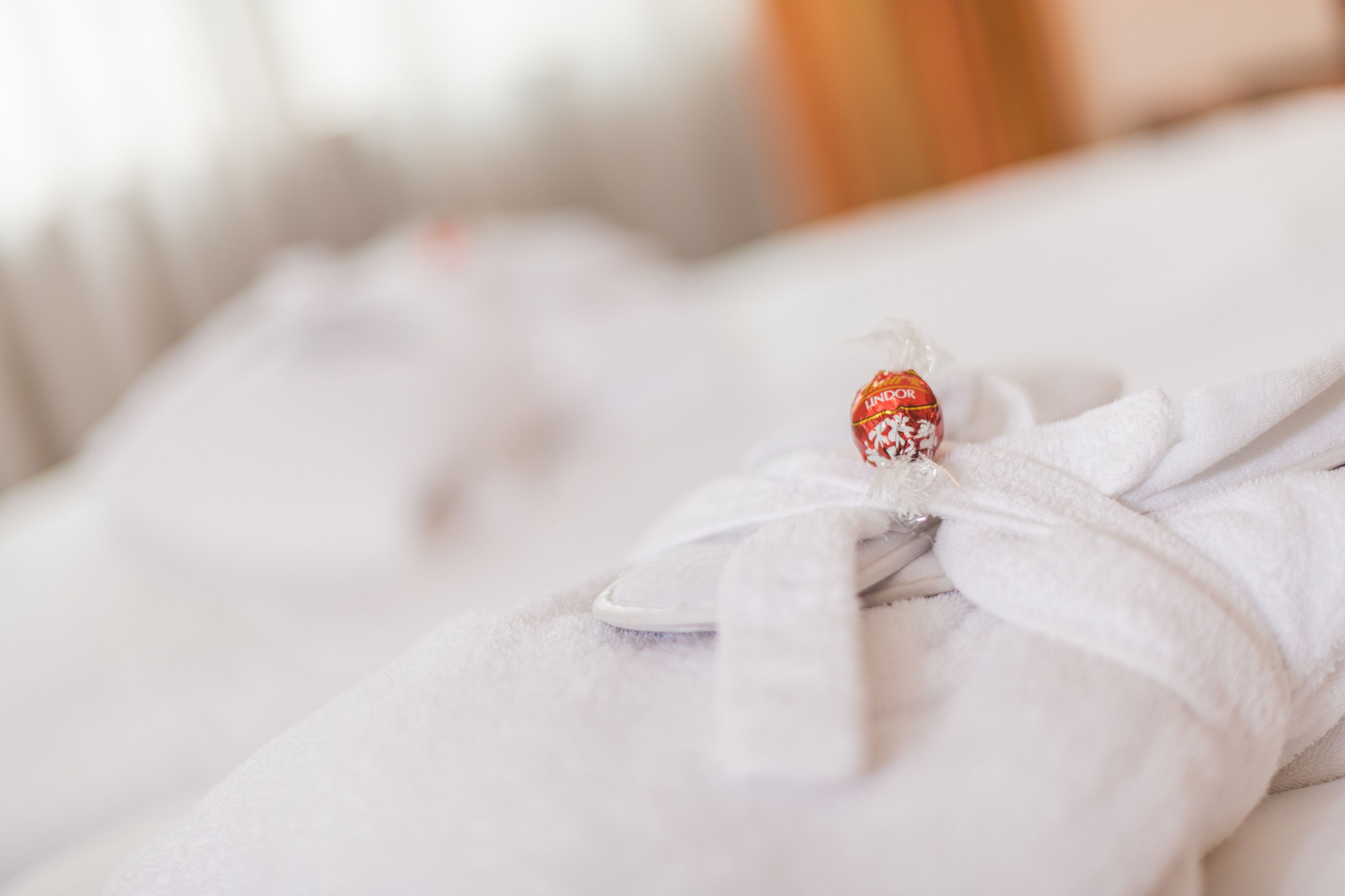 Una cama bien hecha con una manta blanca y una almohada decorativa.