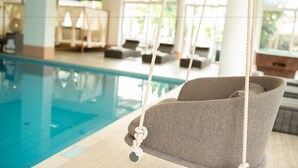 A poolside area with a swing chair, lounge chairs, and a view of the pool. - Hotel Weingarten (Appiano Sulla Strada del Vino)