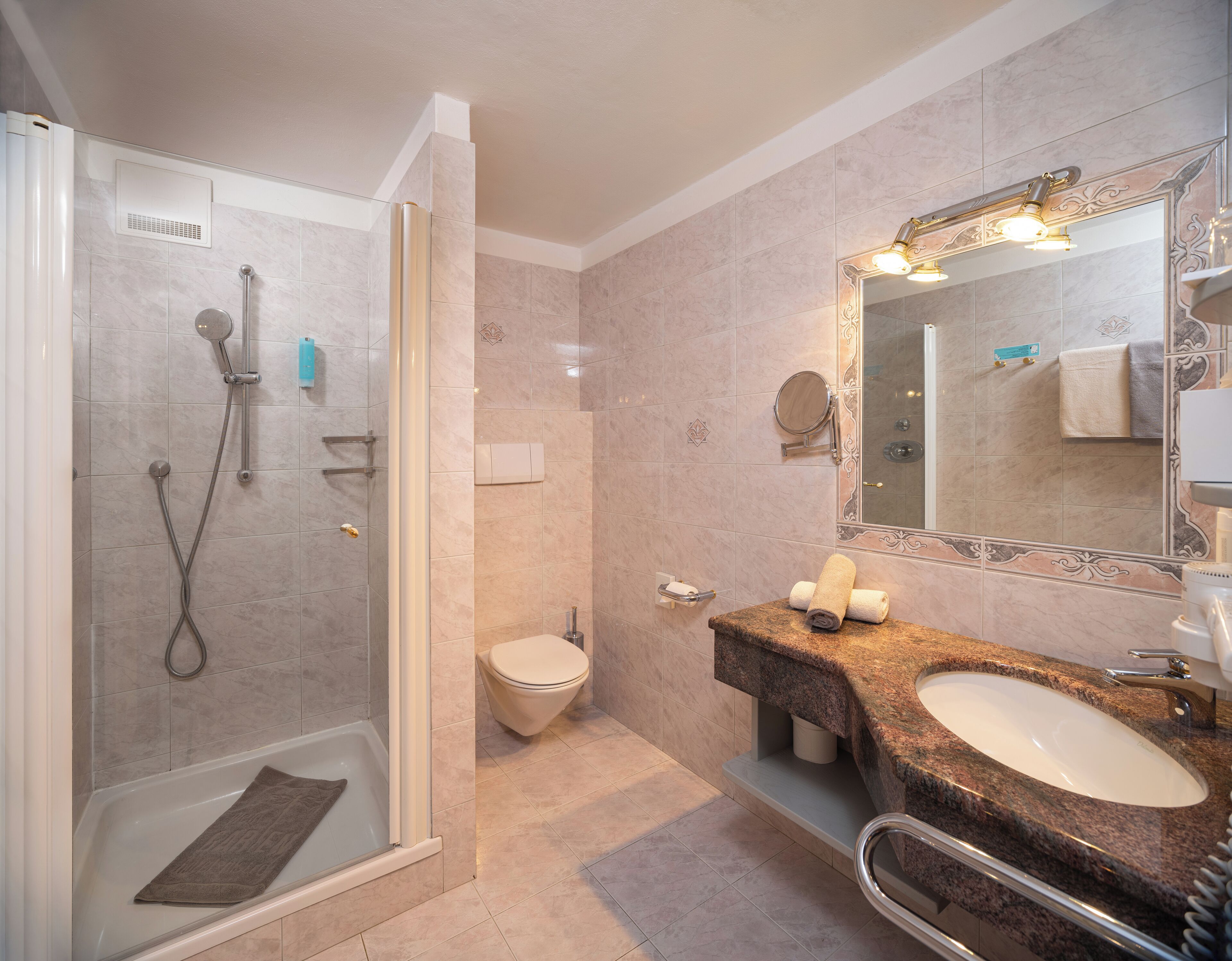 Un baño moderno con ducha envuelta en vidrio, inodoro y tocador con lavabo y espejo.
