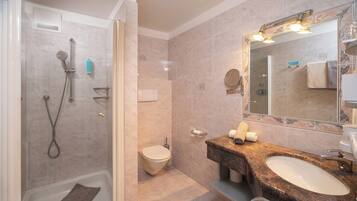 Un baño moderno con ducha envuelta en vidrio, inodoro y tocador con lavabo y espejo.