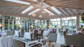 A spacious restaurant with high ceilings, large windows, and wicker furniture. - Hotel Weingarten (Appiano Sulla Strada del Vino)