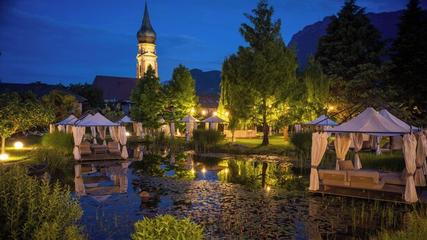 A serene lakeside setting with a gazebo, a pond with lily pads, and a distant church tower. - Hotel Weingarten (Appiano Sulla Strada del Vino)
