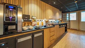 A modern kitchen with a built-in coffee machine, a refrigerator, and a breakfast bar with various food items. - Auberge du Cheval Blanc (Baud)