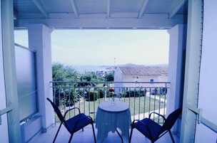 Un balcón con dos sillas y una mesa, con vistas a una zona residencial con casas y vegetación.