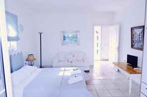 Une chambre d’hôtel avec un lit, un canapé, une télévision et un tableau au mur.