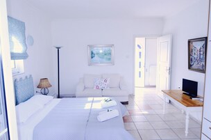 Una habitación de hotel con una cama, un sofá, un televisor y un cuadro en la pared.
