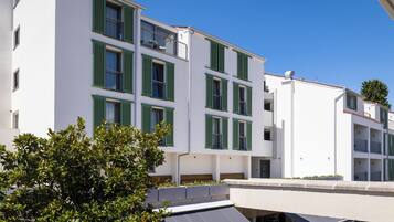 Un immeuble à plusieurs étages, doté d’une façade blanche et de volets verts.