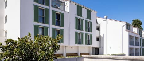 A multi-story building with a white facade and green window shutters.