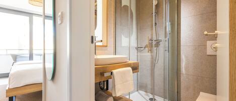 A modern bathroom with a glass-enclosed shower, a white sink, and a wooden vanity.