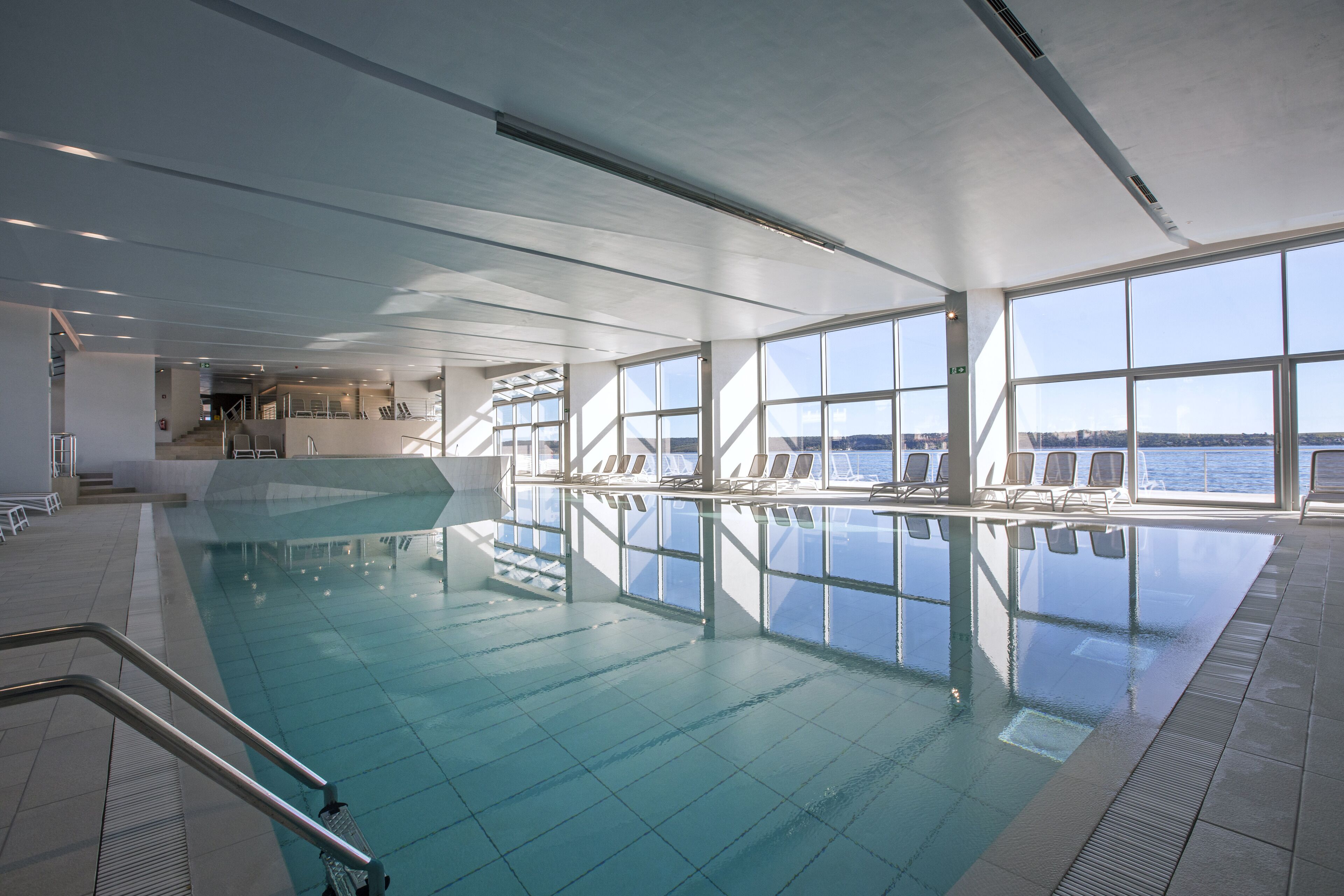 Une grande piscine intérieure offrant une vue dégagée sur la mer grâce à de larges baies vitrées.