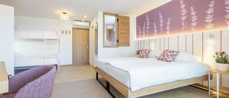 A bedroom with a bunk bed, a single bed, a chair, a bedside table, and a wall with floral patterns.