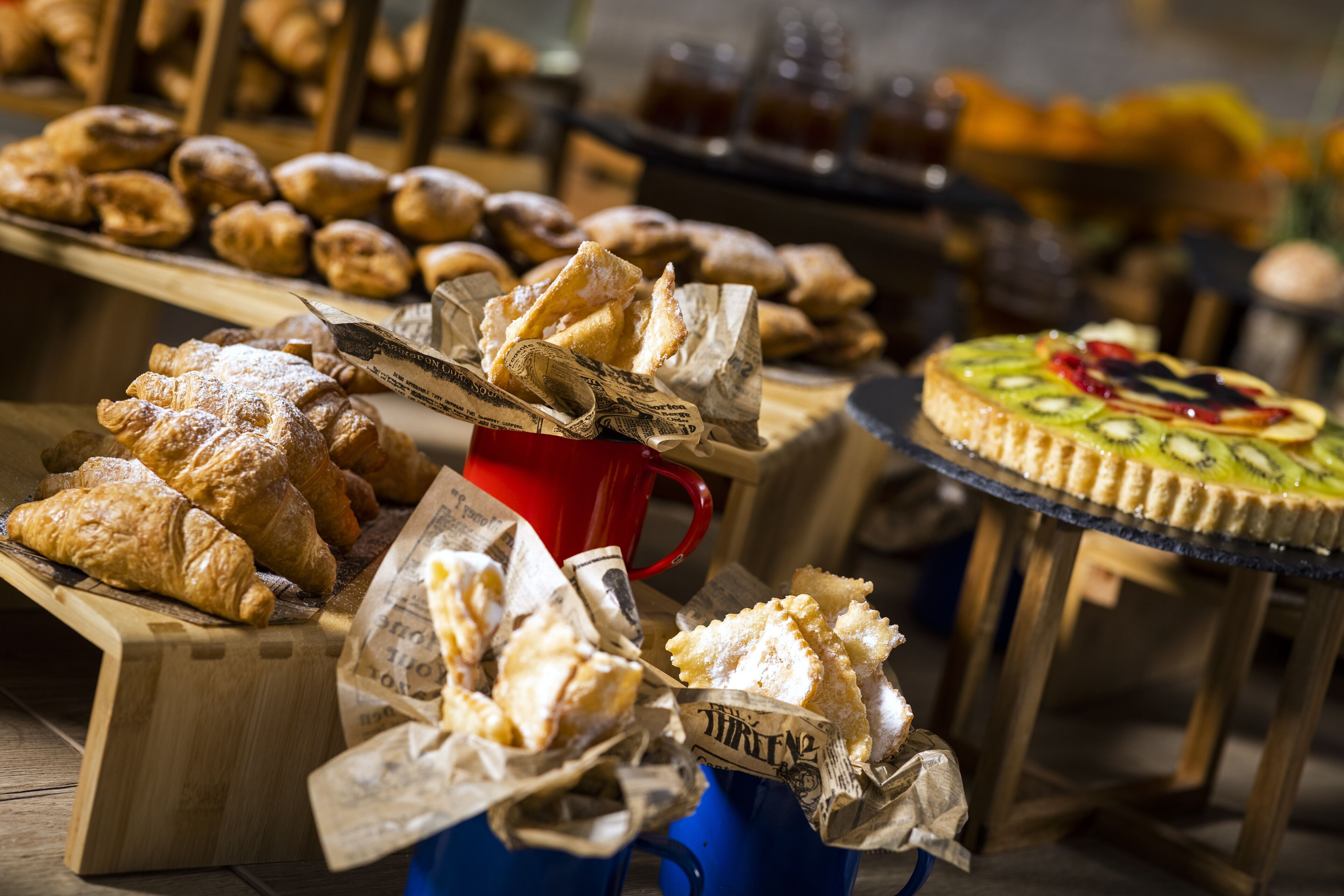 Una variedad de pasteles y postres exhibidos sobre bases y mesas de madera.