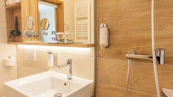 Une salle de bain moderne avec un meuble-lavabo à deux vasques, un grand miroir, une douchette à main et un lambris en bois.