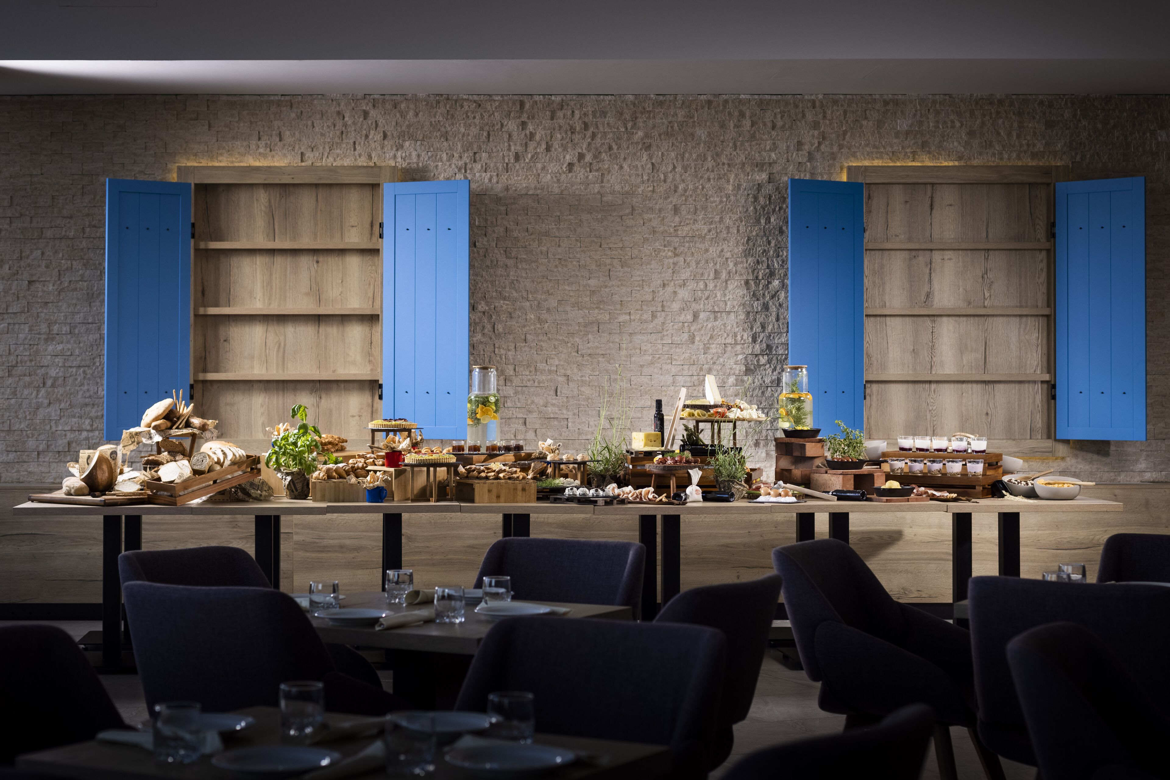 Een restaurant met een rustieke bakstenen muur, houten tafels en blauwe luiken.