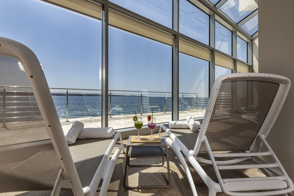 A sunlit deck with a table, lounge chairs, and a view of the sea. - Hotel Histrion - Sava Hotels & Resorts (Piran)