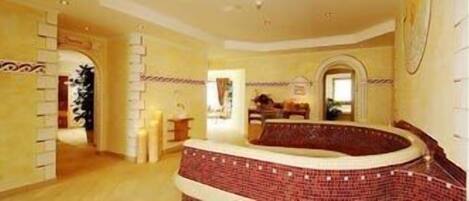 A spacious room with a curved brick wall, a wooden floor, and a large window.