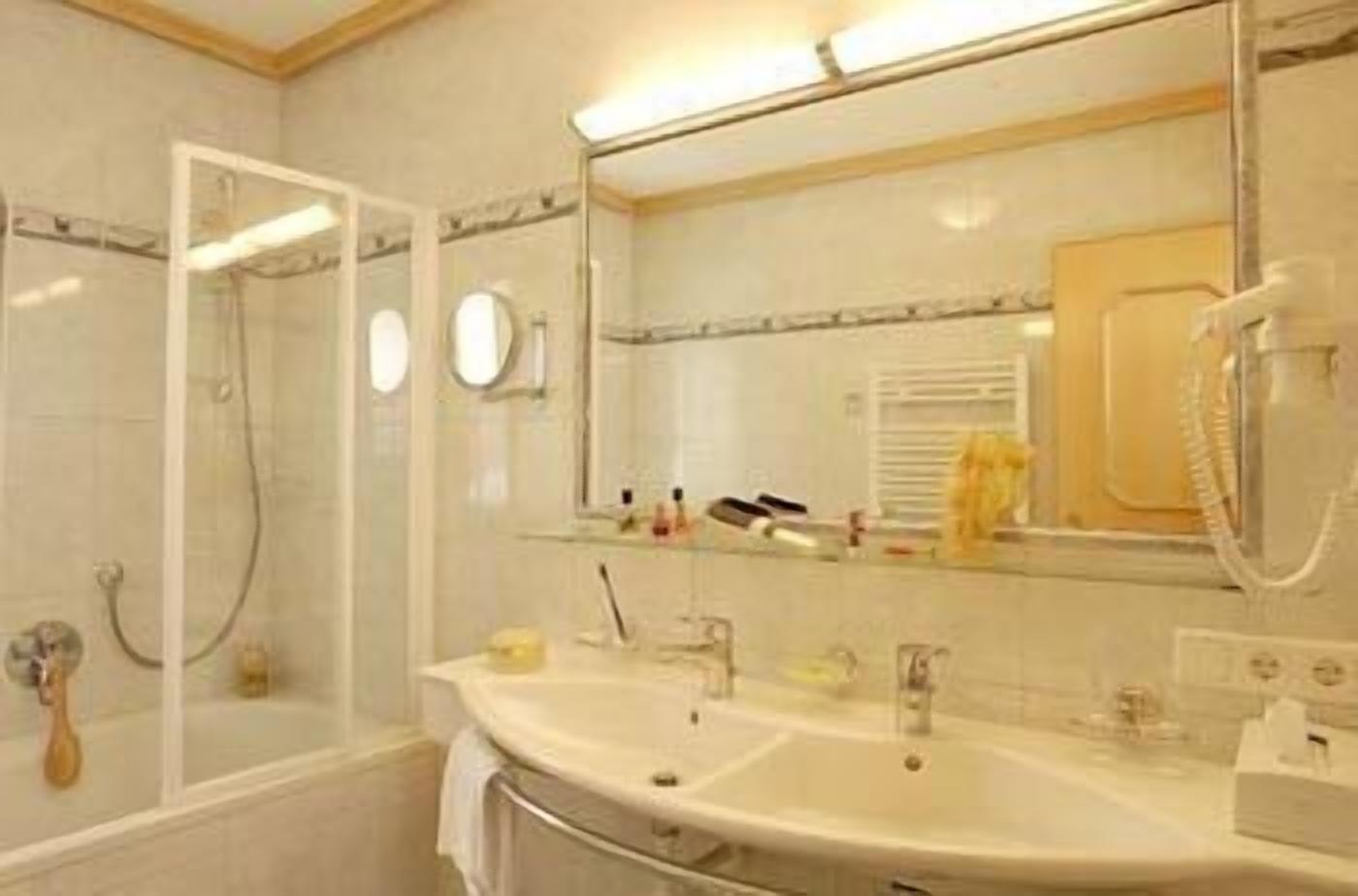 Un baño con cabina de ducha de vidrio, lavabo con espejo y teléfono.