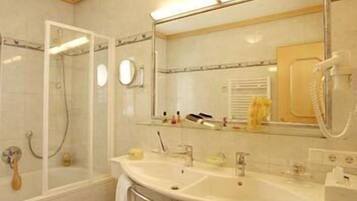Un baño con cabina de ducha de vidrio, lavabo con espejo y teléfono.