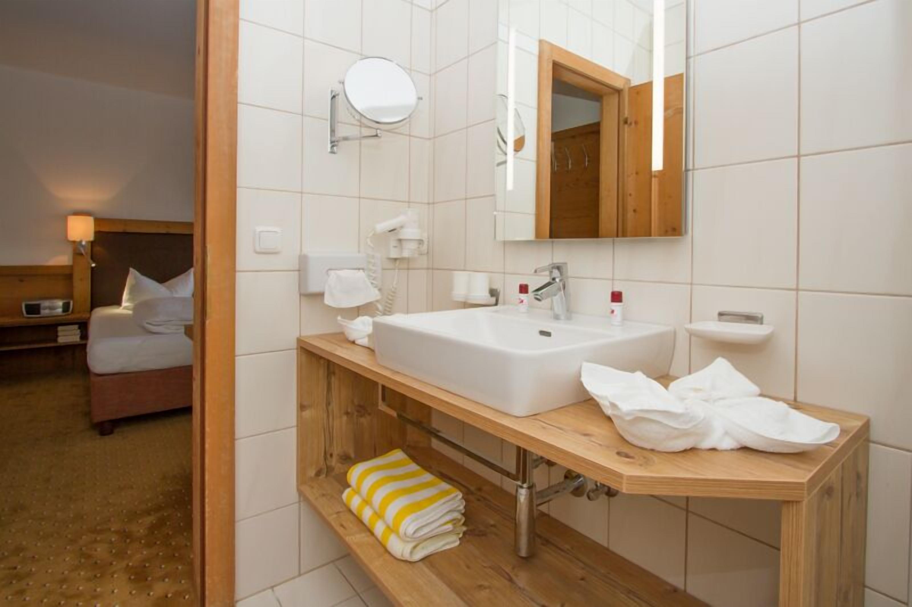 A modern bathroom with a wooden vanity, a large mirror, and a separate toilet area.