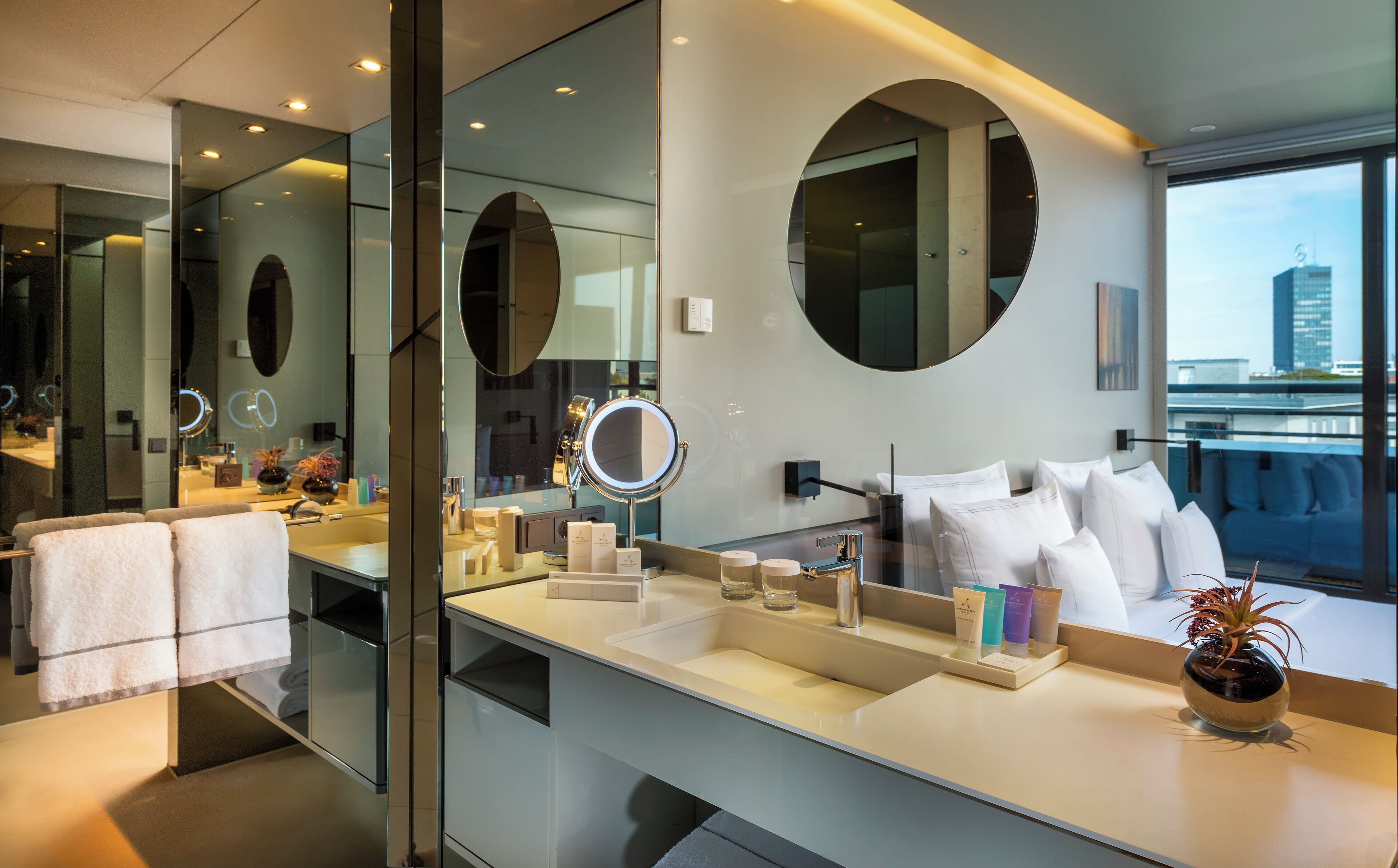 A modern bathroom with a large mirror, a vanity with a sink, and a potted plant.