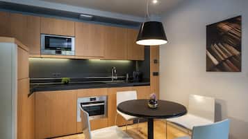A modern kitchen with wooden cabinets, stainless steel appliances, and a black dining table with white chairs.