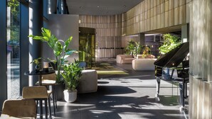 Eine moderne Lobby mit einem Flügel, Sitzbereichen und Topfpflanzen.