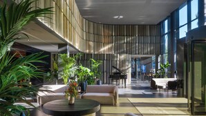 Eine geräumige Lobby mit einem Flügel, bequemen Sitzgelegenheiten und viel Grün.