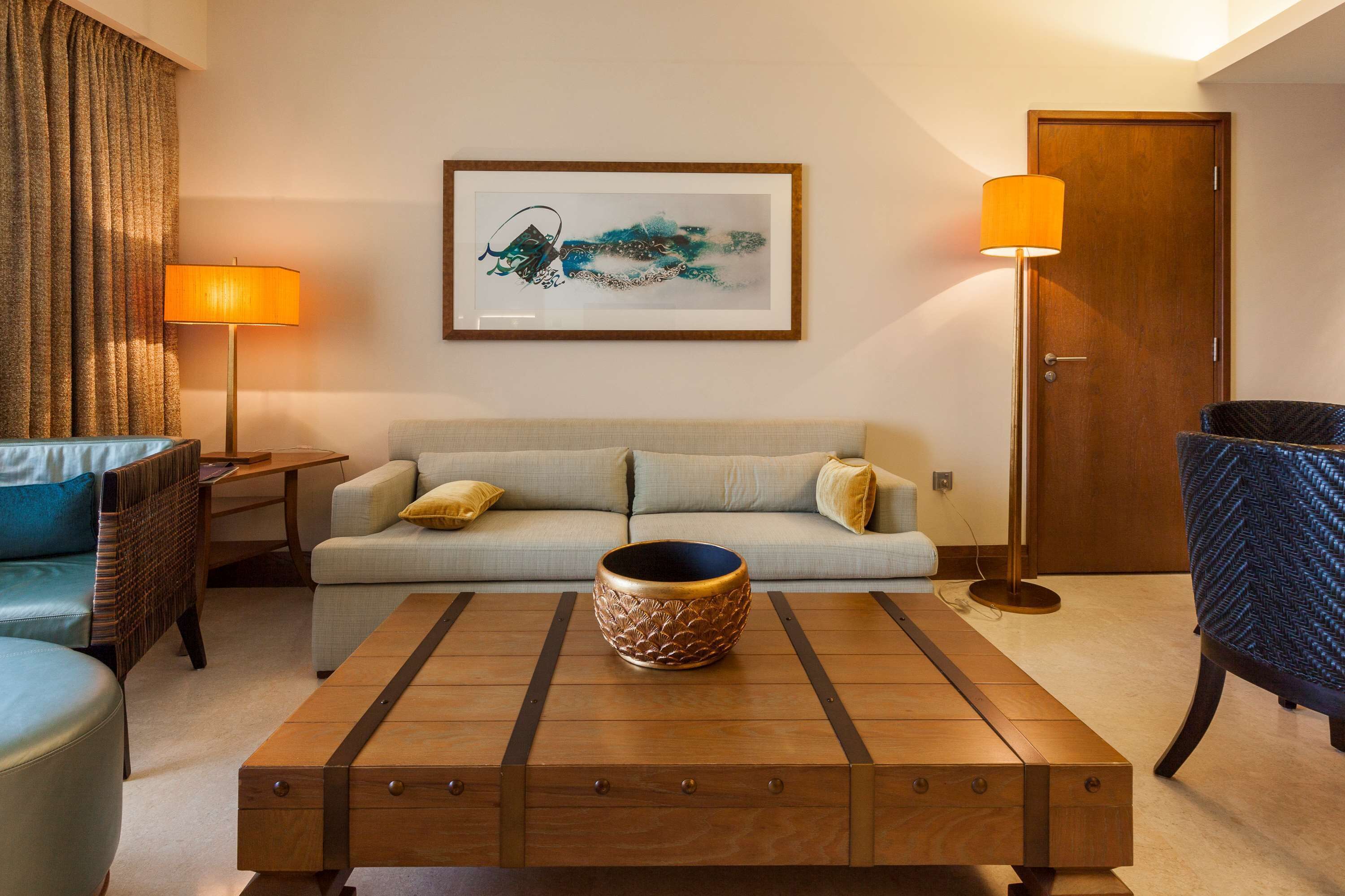 Un salon moderne avec un canapé, une table basse agrémentée d’un vase décoratif, une lampe et une œuvre d’art encadrée accrochée au mur.