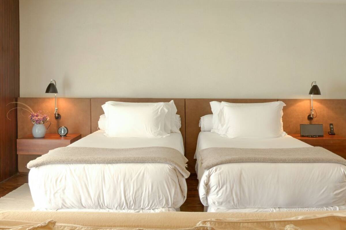 Habitación doble con dos camas, mesitas de noche, lámparas, un mapa en la pared y suelo de madera.