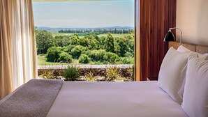 Una cama con vista a un paisaje verde a través de una ventana.