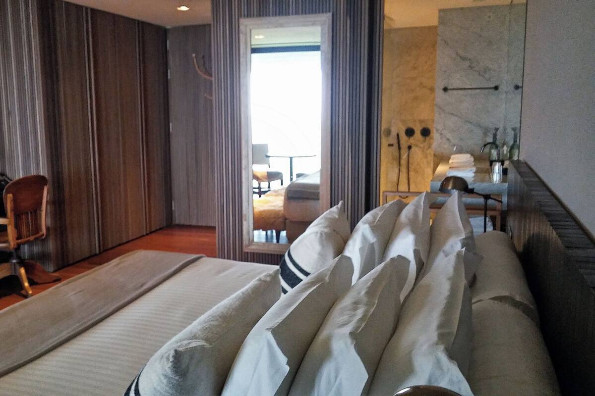 Habitación de hotel con una cama grande, un escritorio con lámpara, una silla y vistas al balcón.