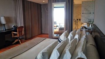 Habitación de hotel con una cama grande, un escritorio con lámpara, una silla y vistas al balcón.