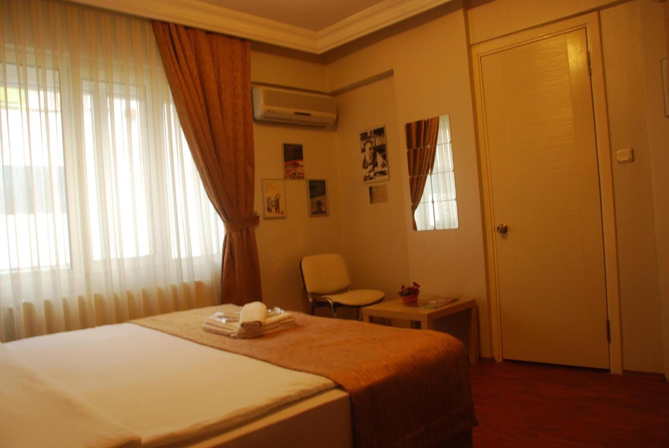 Habitación de hotel con una cama, una silla, una mesita y una puerta.