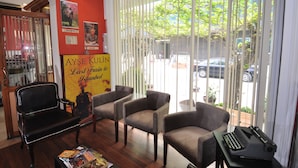 A room with a black leather chair, three grey armchairs, a small table with a typewriter, and a poster on the wall. - Mini Fuar Hotel (Izmir)