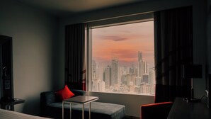 A modern hotel room with a large window offering a city skyline view.