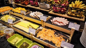 Un buffet proposant une variété de plats, notamment des fromages, du poulet et du saumon fumé.