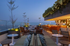 A rooftop bar with seating and a bar area, overlooking a cityscape. - Hilton Copacabana Rio de Janeiro (Rio de Janeiro)