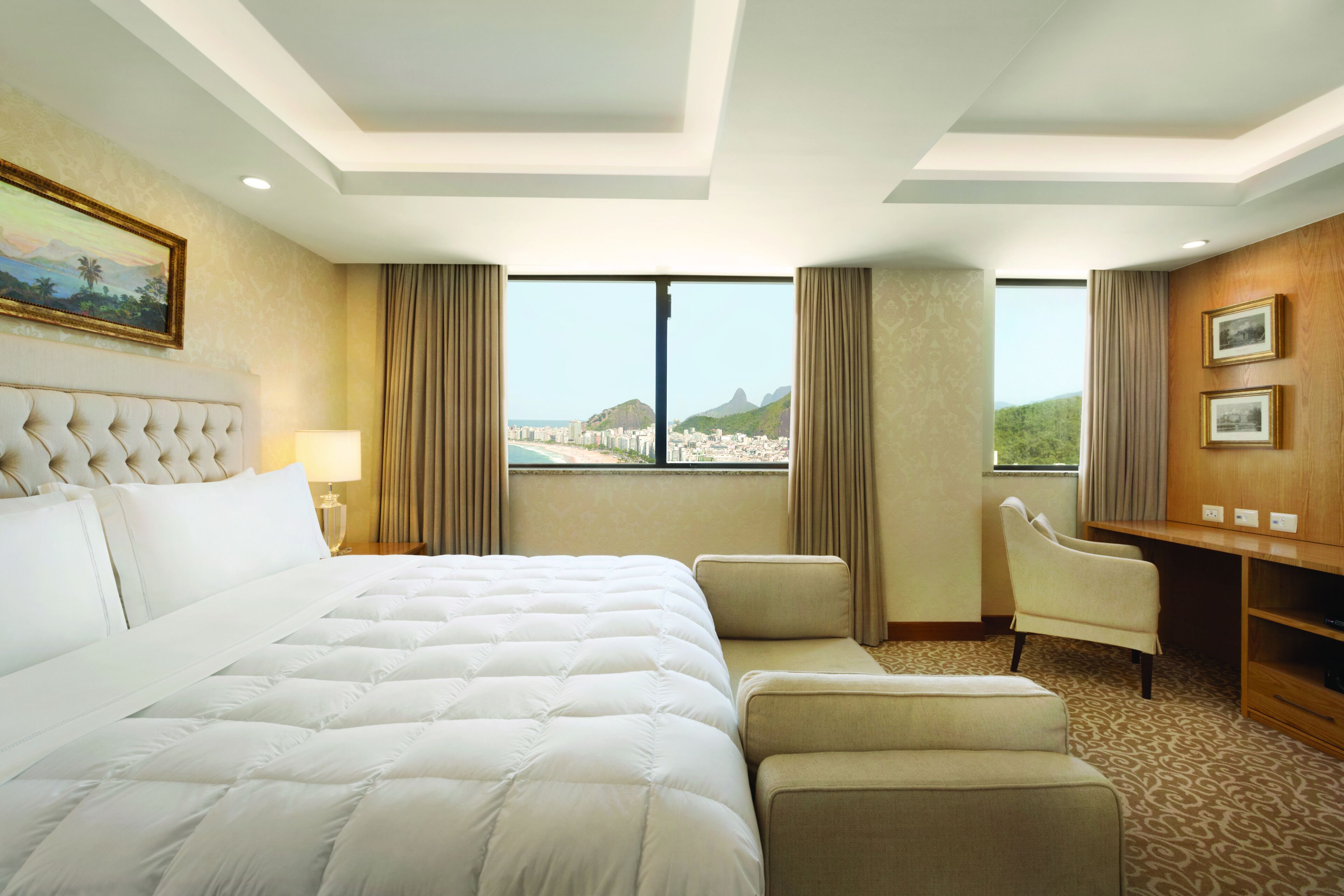 Quarto de hotel com uma cama grande, uma escrivaninha, uma cadeira e vista para a cidade.