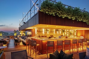 Un bar situé sur le toit, avec un comptoir, un espace salon et une vue sur le paysage urbain.