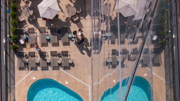 Vista aérea de una zona de piscina con sillones de descanso y sombrillas.