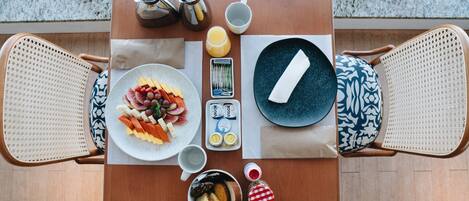 A breakfast table with plates of food, a coffee pot, a cup, and a bottle of jam.