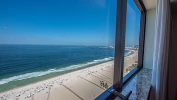 A beach view from a window overlooking a sandy beach with umbrellas and people.