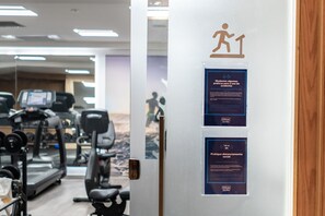 A gym with treadmills, weights, and exercise equipment. There are signs on the door about social distancing and hygiene practices. - Hilton Copacabana Rio de Janeiro (Rio de Janeiro)