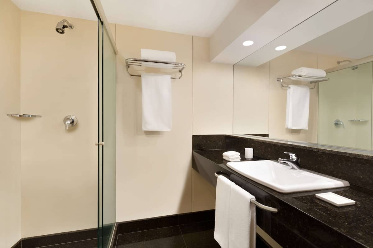 Ein modernes Badezimmer mit Duschkabine aus Glas, Waschbecken mit Spiegel und Handtuchhalter.