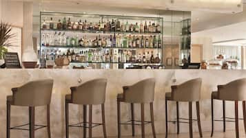A bar area with multiple liquor bottles, a glass display case, and four bar stools.