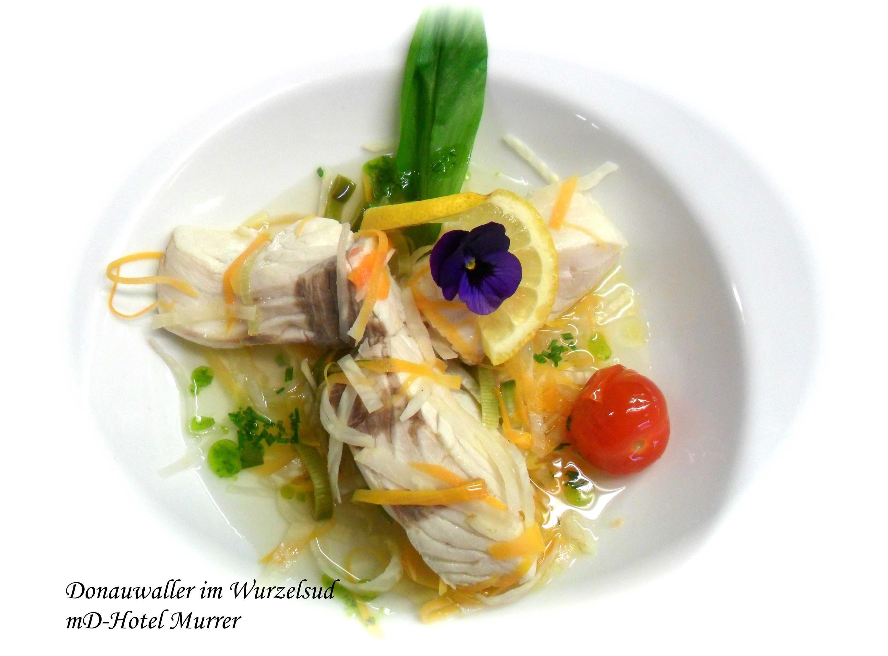 Un plato con pollo, verduras y una flor como adorno.